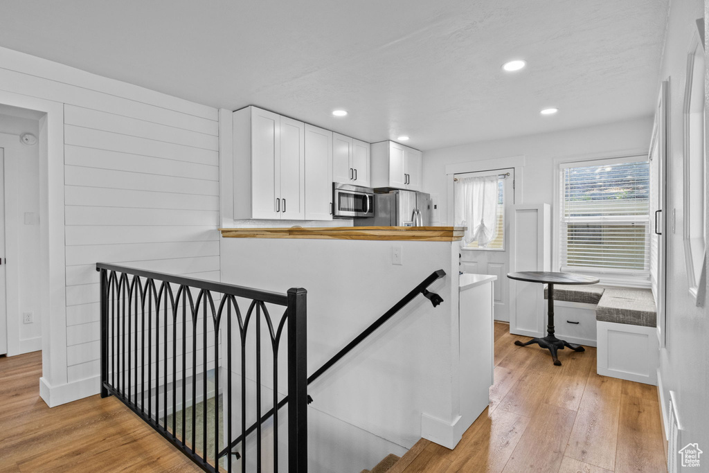 Kitchen with appliances with stainless steel finishes, light wood finished floors, white cabinets, and recessed lighting