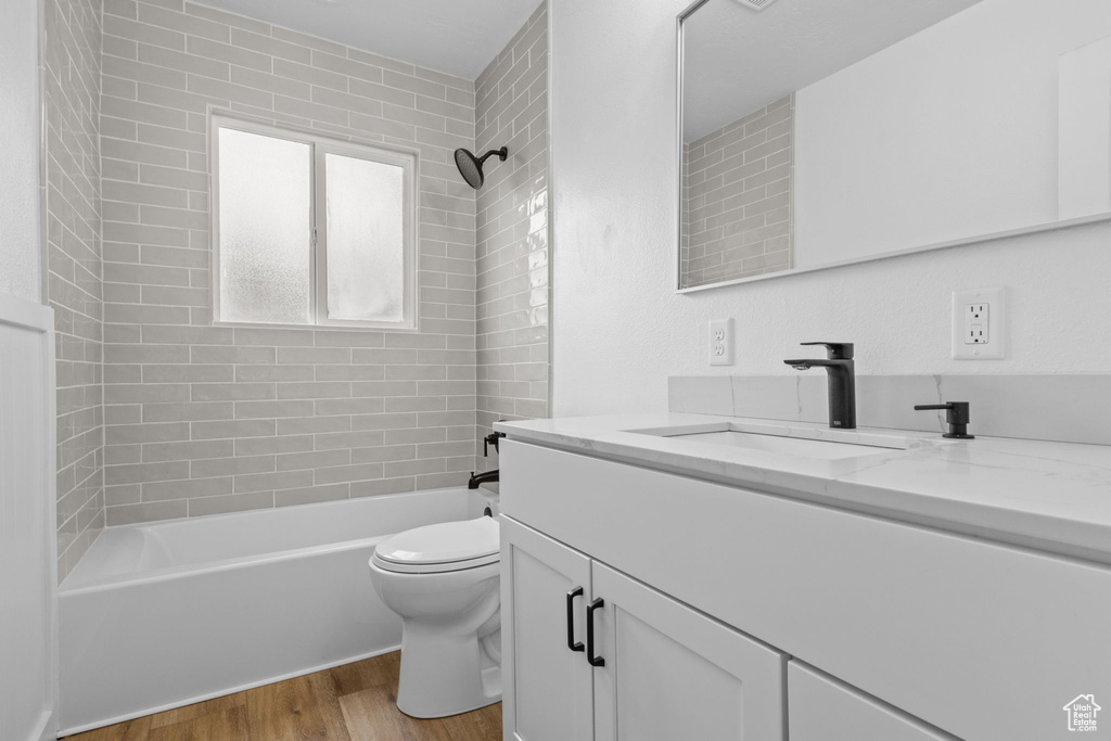 Bathroom featuring vanity, wood finished floors, toilet, and  shower combination