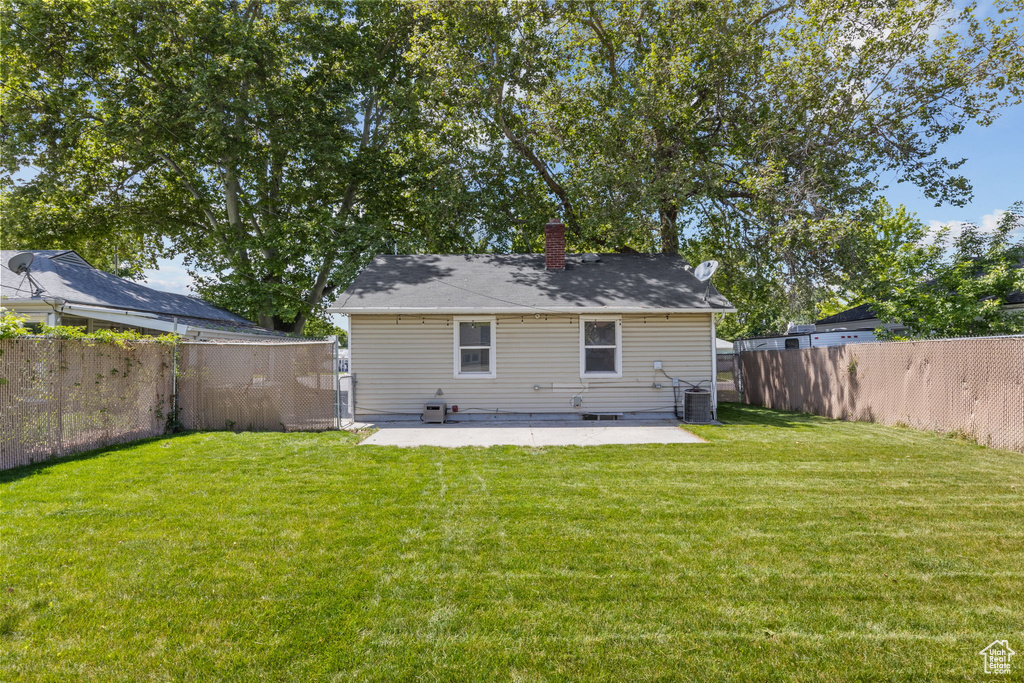 Rear view of property with a patio, a chimney, and central AC