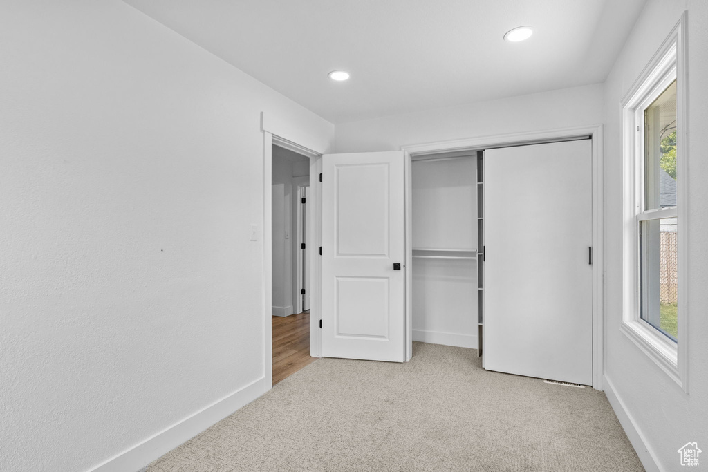 Unfurnished bedroom featuring light colored carpet, multiple windows, recessed lighting, a closet, and baseboards