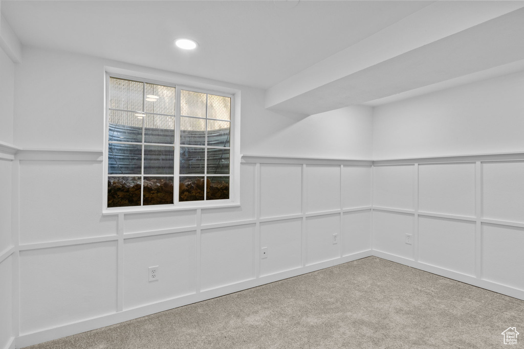 Empty room featuring carpet flooring, a decorative wall, a wainscoted wall, and recessed lighting
