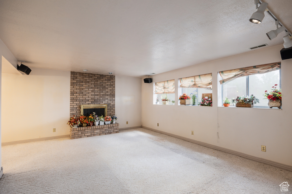 Unfurnished living room featuring carpet flooring, a brick fireplace, and baseboards
