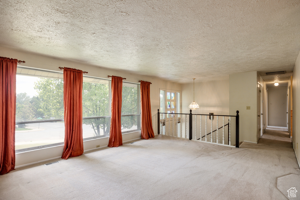 Unfurnished room with carpet floors, a textured ceiling, and baseboards