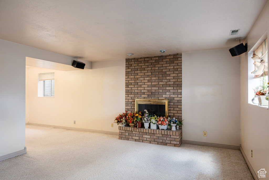 Unfurnished living room with carpet floors, baseboards, and a fireplace