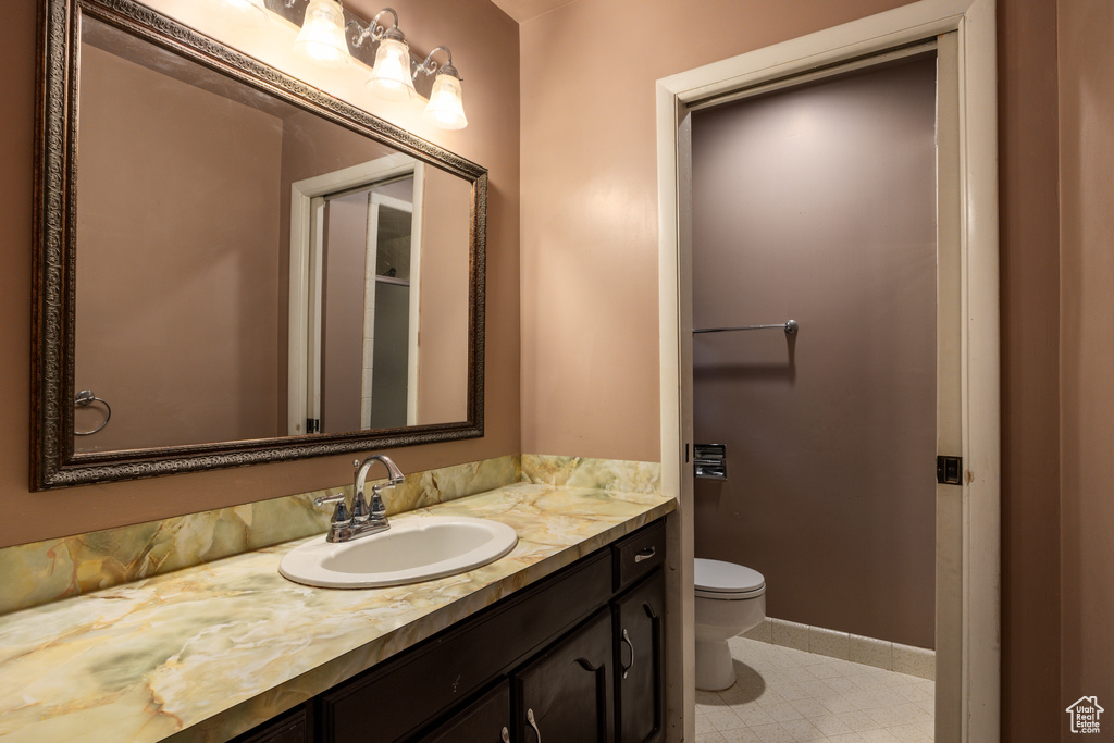 Bathroom featuring toilet, vanity, baseboards, and tile patterned floors