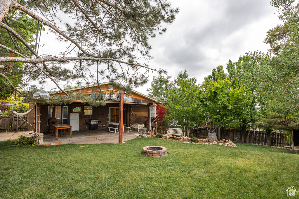 View of yard with an outdoor fire pit and a patio