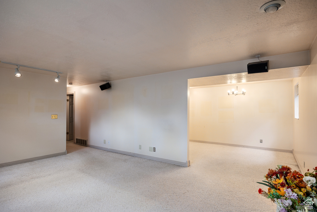 Carpeted spare room featuring track lighting and baseboards