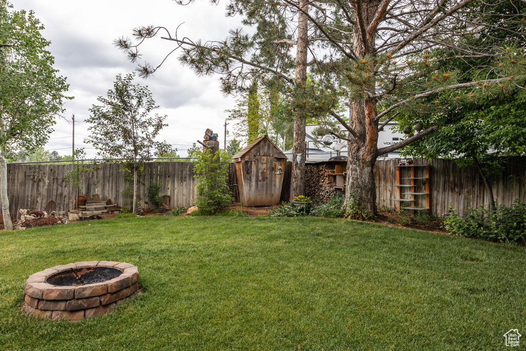 View of yard with a fire pit and a storage unit