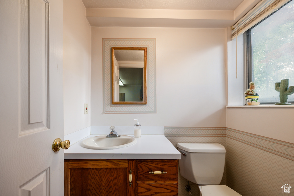Bathroom with vanity, toilet, and a wainscoted wall