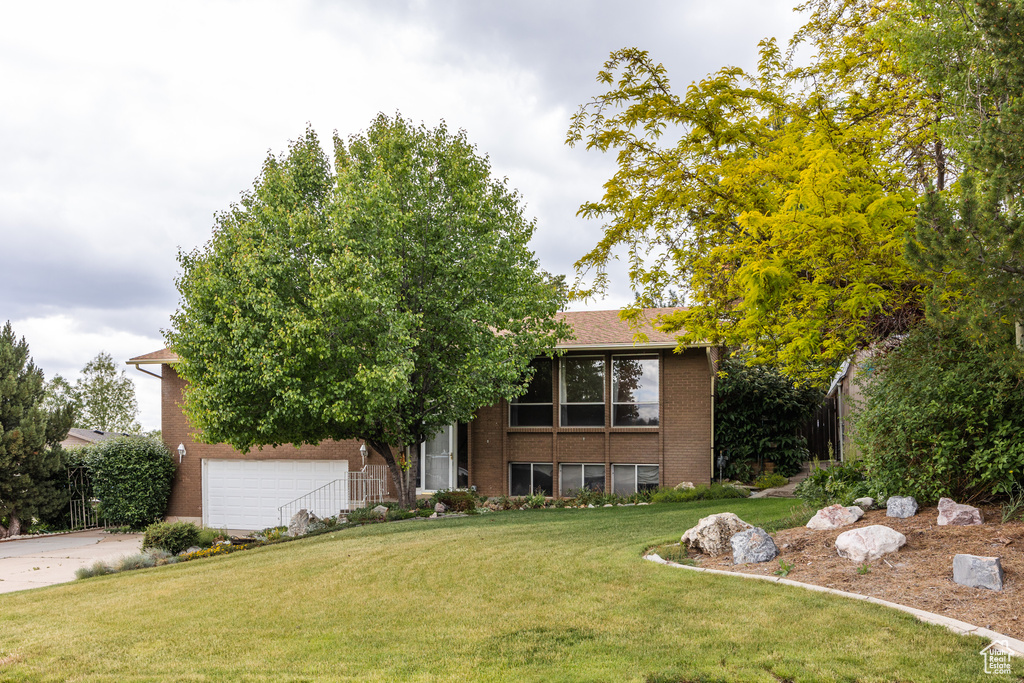 View of front of house with brick siding, a front lawn, a garage, and concrete driveway
