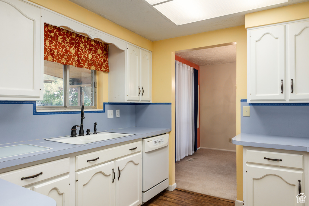 Kitchen featuring dishwasher, a sink, white cabinets, and light countertops