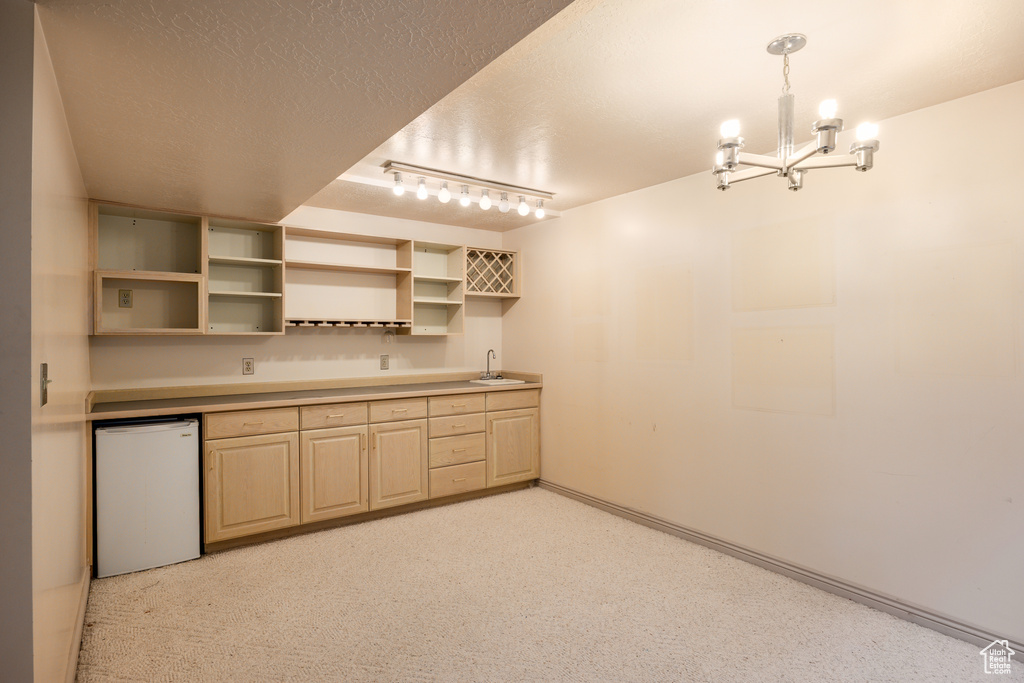 Kitchen with refrigerator, a sink, a chandelier, light brown cabinetry, and open shelves