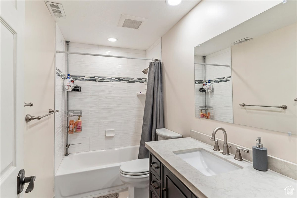 Full bath with vanity, toilet, shower / bath combo with shower curtain, and recessed lighting