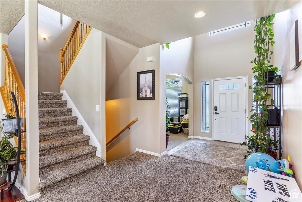 Entryway with arched walkways, stairs, recessed lighting, carpet, and baseboards