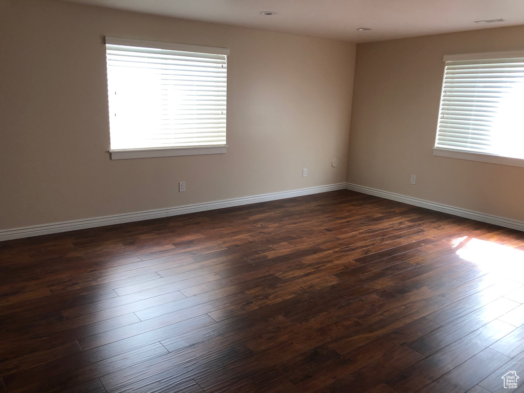 Unfurnished room with plenty of natural light, dark wood-style flooring, and baseboards