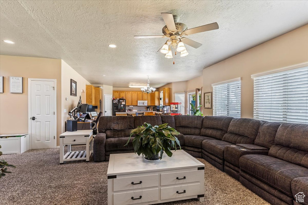 Carpeted living room featuring a textured ceiling, a chandelier, ceiling fan, and recessed lighting