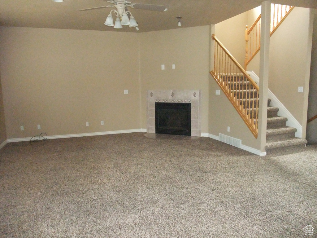 Unfurnished living room featuring stairs, ceiling fan, carpet flooring, a fireplace, and baseboards