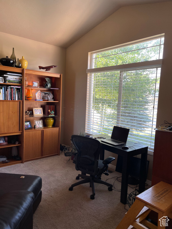 Home office featuring lofted ceiling and light carpet