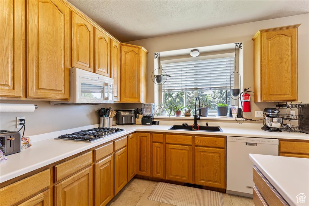 Kitchen featuring white appliances, a sink, light countertops, and light tile patterned floors