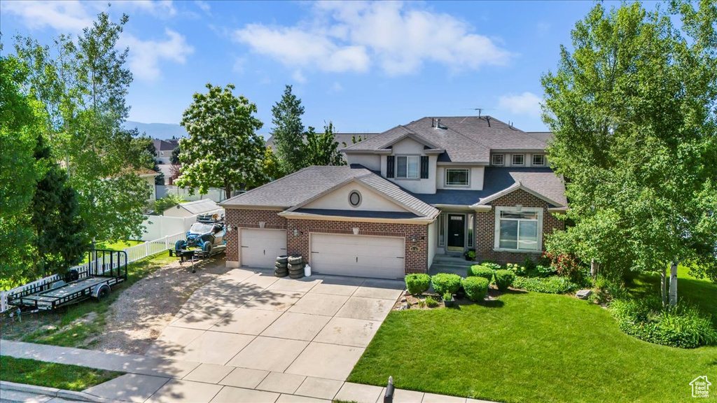 View of front facade featuring an attached garage, driveway, brick siding, and a shingled roof