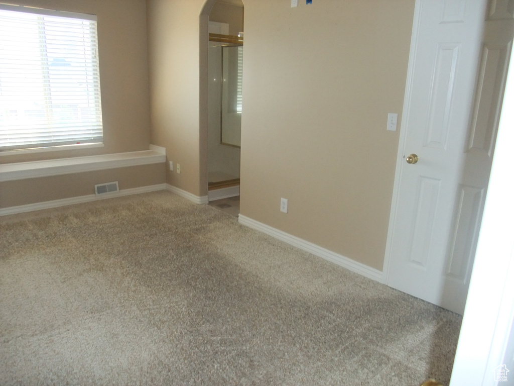 Empty room with arched walkways, carpet floors, and baseboards