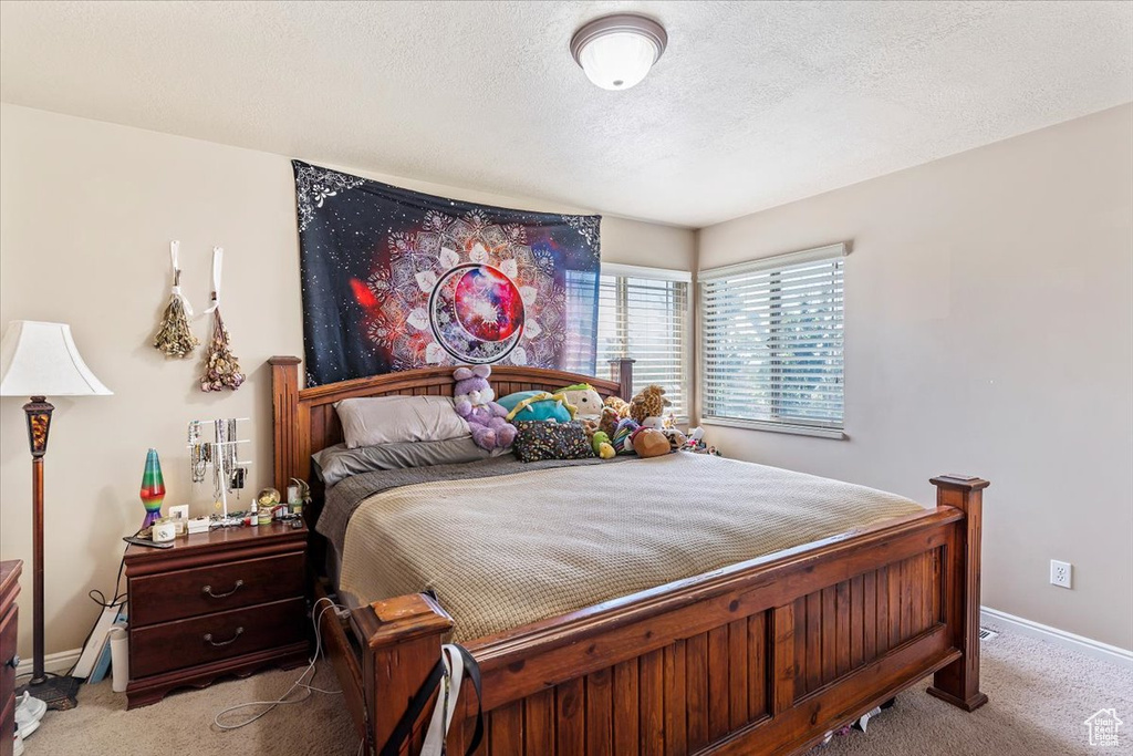 Carpeted bedroom featuring a textured ceiling and baseboards