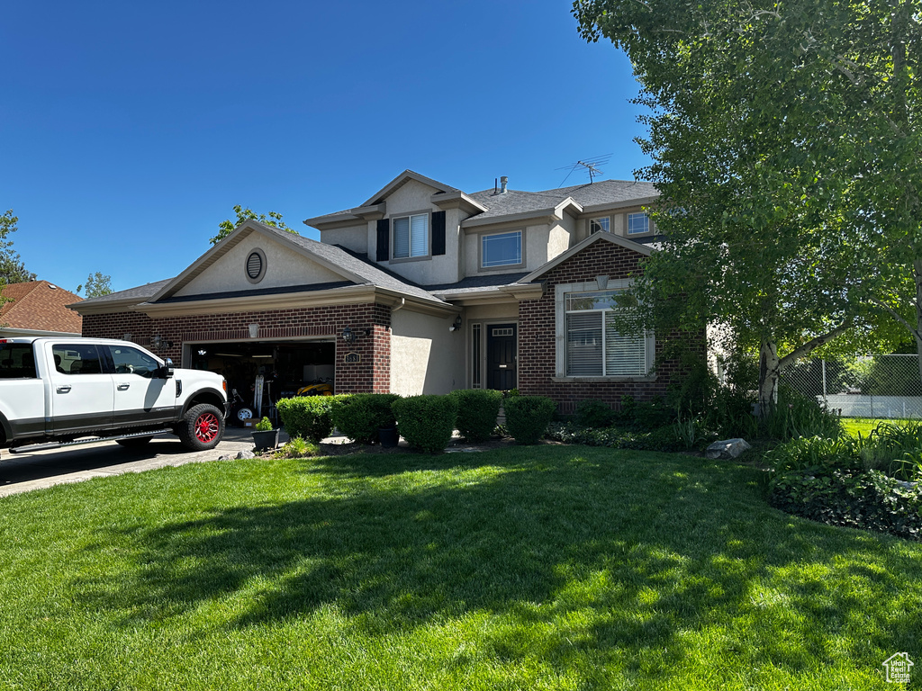 Traditional-style home with an attached garage, stucco siding, brick siding, and a front lawn