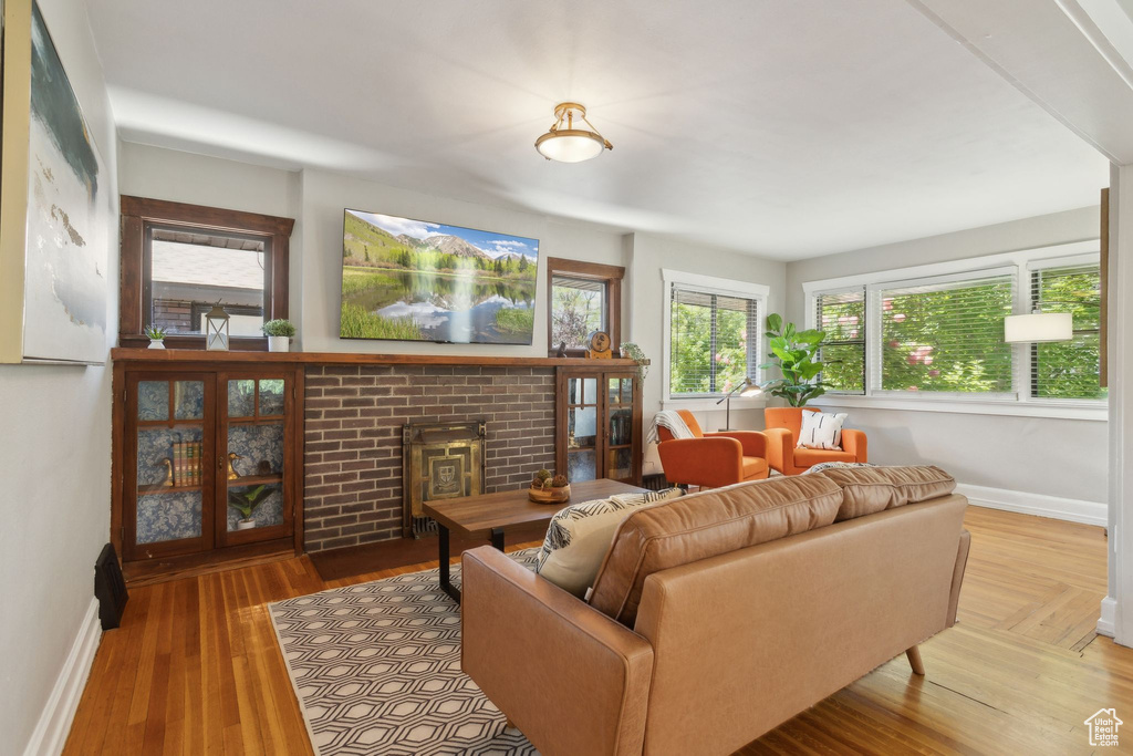 Living area with a brick fireplace, baseboards, and wood finished floors