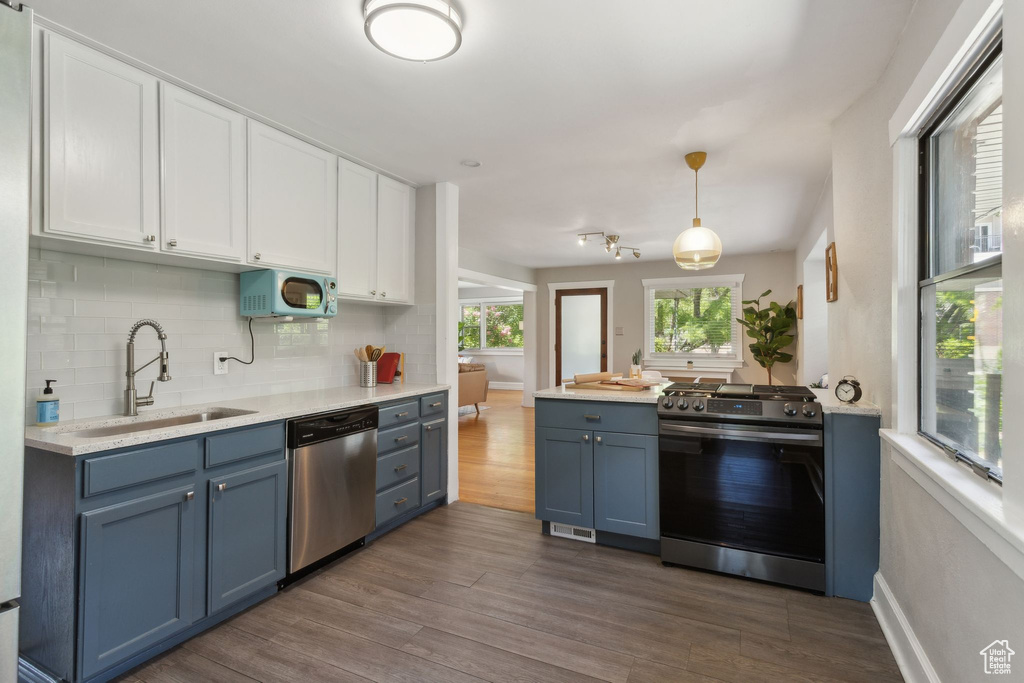 Kitchen with stainless steel appliances, a sink, blue cabinets, white cabinetry, and dark wood-style flooring
