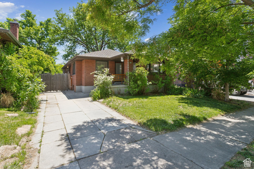 View of front of property featuring brick siding, concrete driveway, and a porch