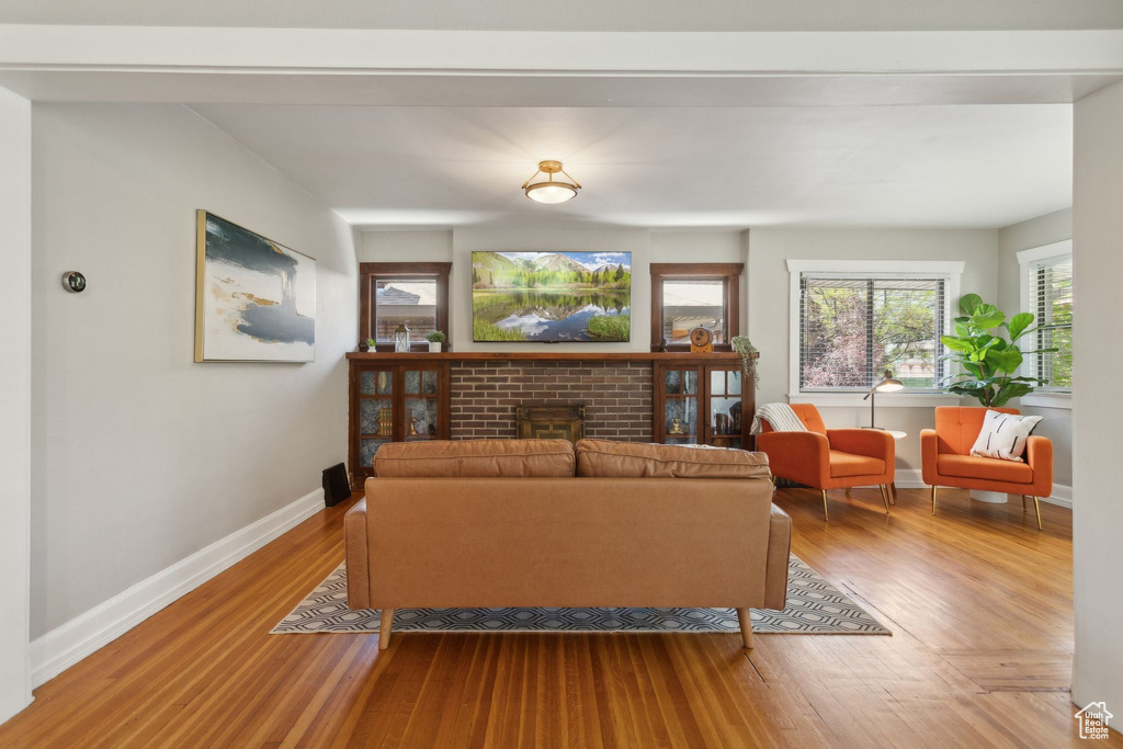 Living room featuring a brick fireplace, wood finished floors, and baseboards