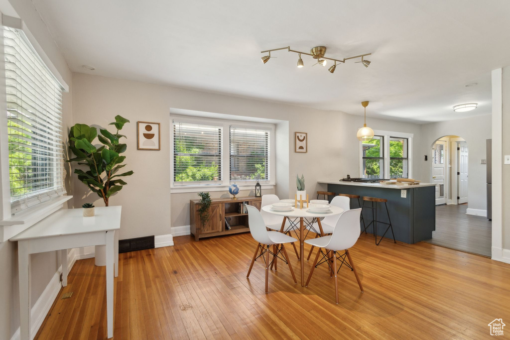 Dining space featuring arched walkways, light wood-style floors, and baseboards