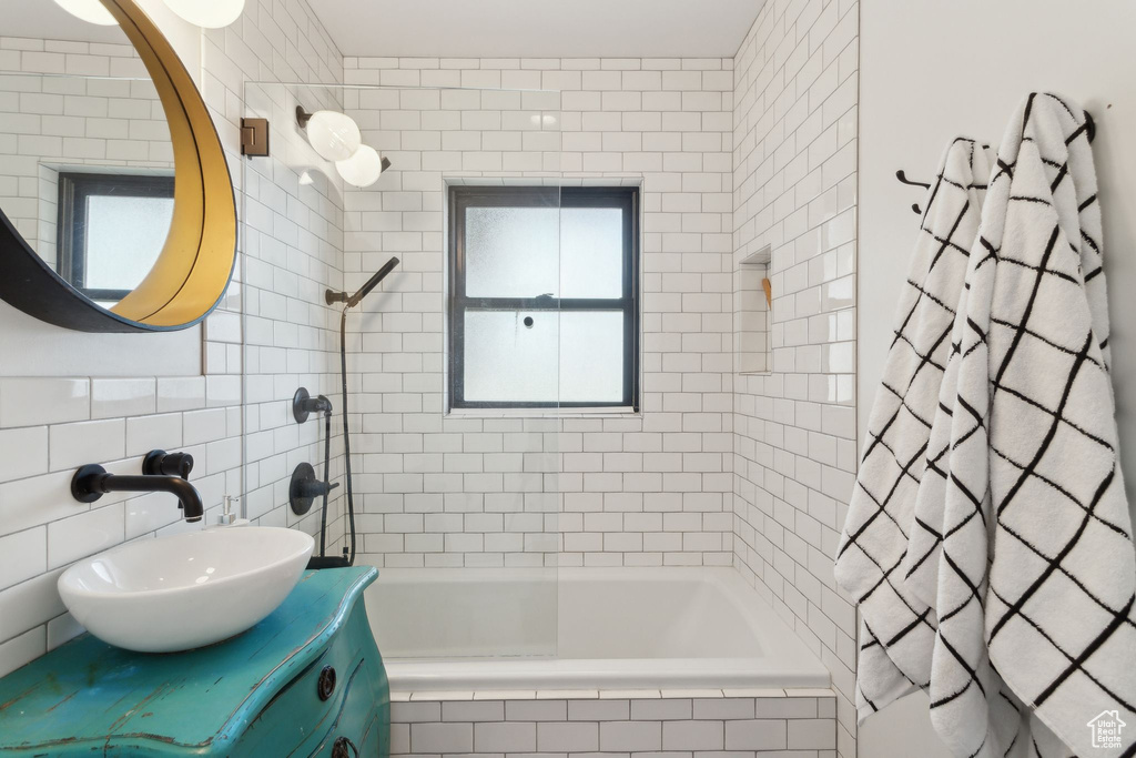 Bathroom featuring tiled shower / bath, tile walls, and vanity