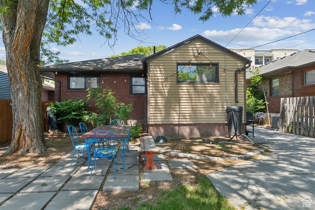 Rear view of property featuring a patio area, cooling unit, brick siding, and outdoor dining space