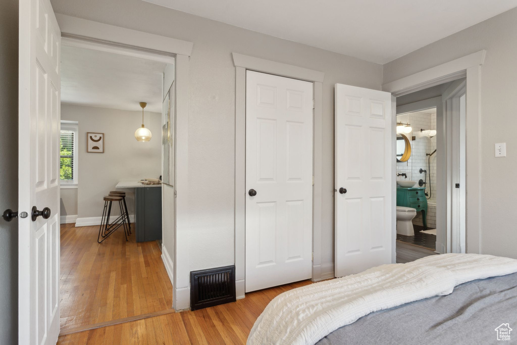 Bedroom featuring light wood-style flooring, baseboards, and ensuite bath