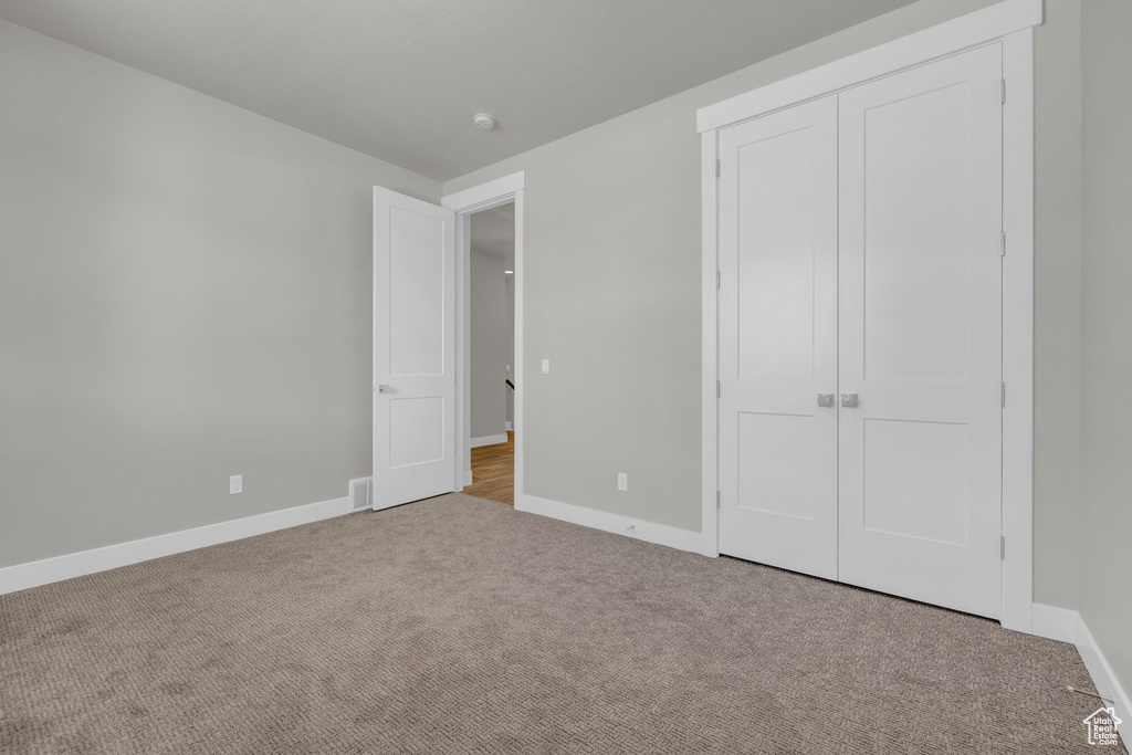 Unfurnished bedroom featuring carpet flooring, baseboards, and a closet
