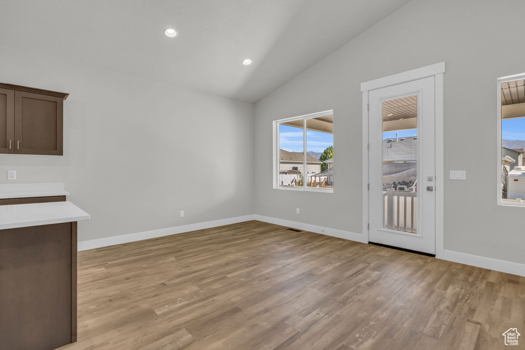Unfurnished living room featuring light wood-style floors, baseboards, recessed lighting, and high vaulted ceiling