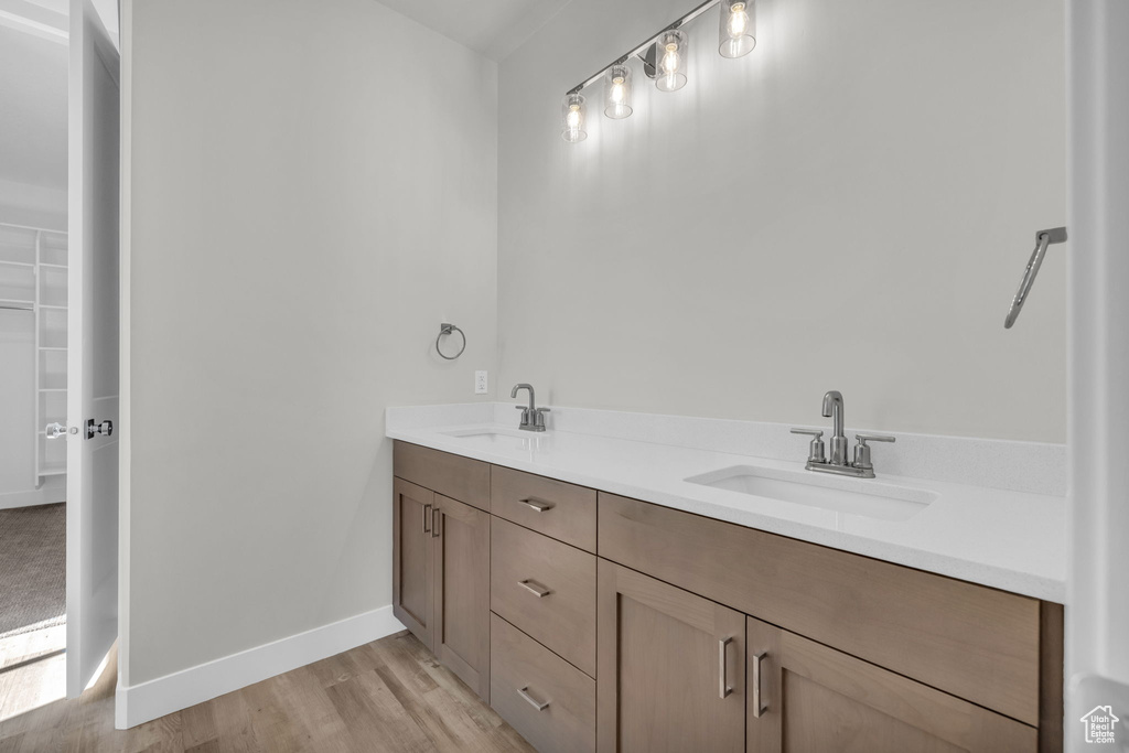 Full bathroom featuring wood finished floors, double vanity, and baseboards