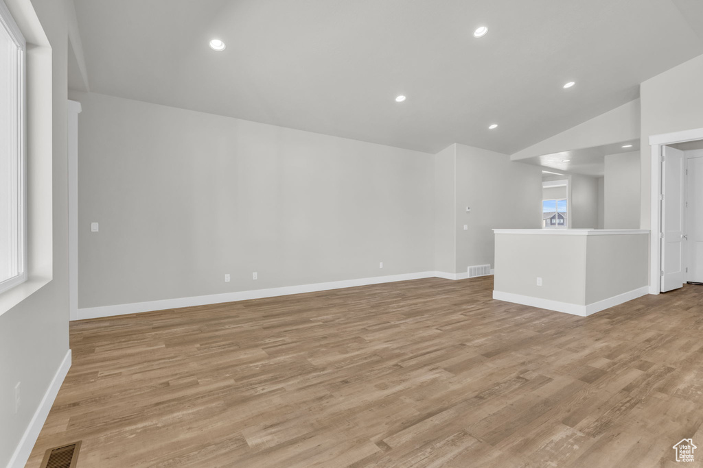 Spare room featuring light wood-style flooring, baseboards, vaulted ceiling, and recessed lighting
