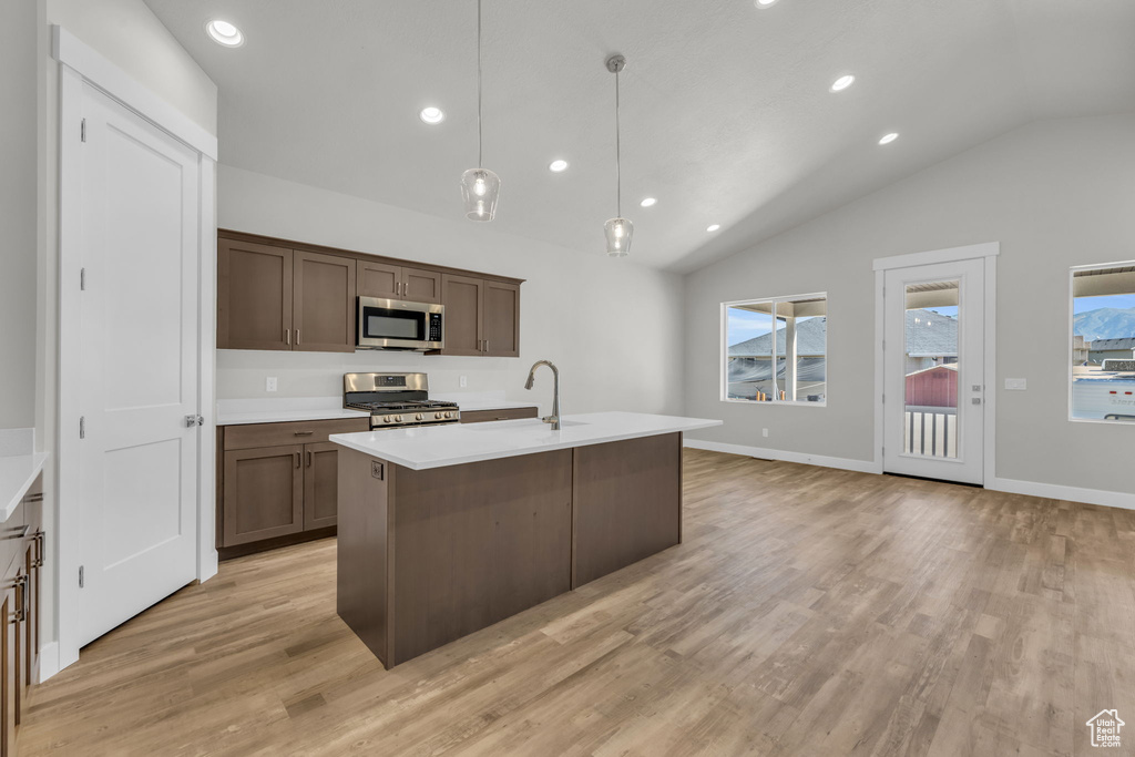 Kitchen featuring appliances with stainless steel finishes, a sink, vaulted ceiling, light wood finished floors, and recessed lighting
