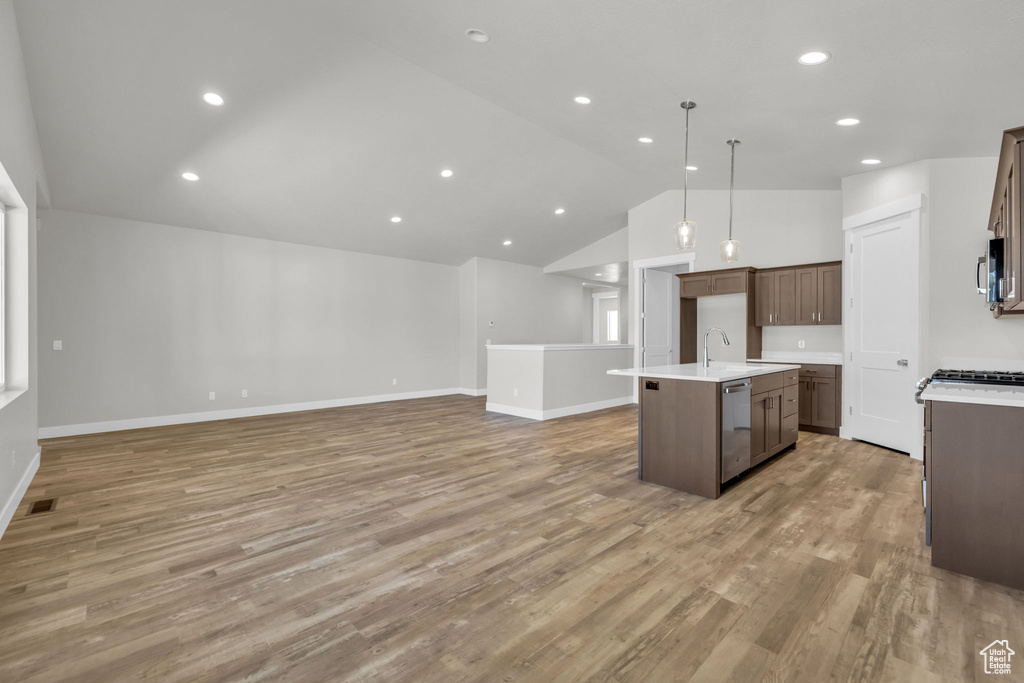 Kitchen featuring open floor plan, a center island with sink, light countertops, light wood-style flooring, and recessed lighting