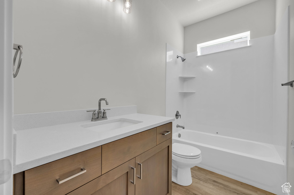 Bathroom featuring toilet, vanity, washtub / shower combination, and wood finished floors