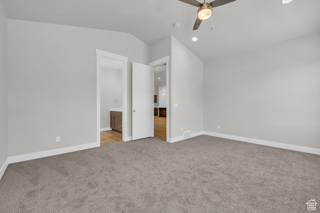 Unfurnished bedroom featuring carpet floors, baseboards, recessed lighting, lofted ceiling, and connected bathroom