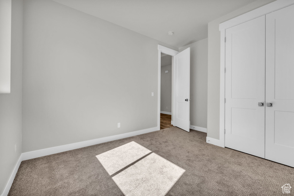 Unfurnished bedroom with carpet flooring, baseboards, and a closet