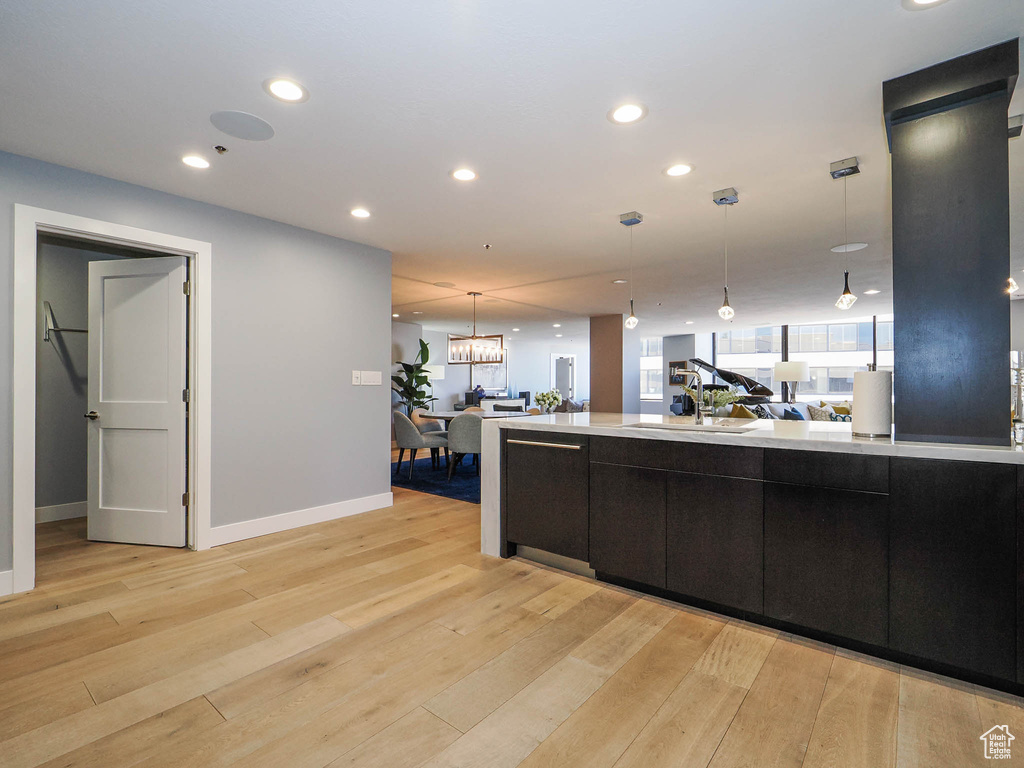 Kitchen with light wood-type flooring, light countertops, pendant lighting, baseboards, and recessed lighting