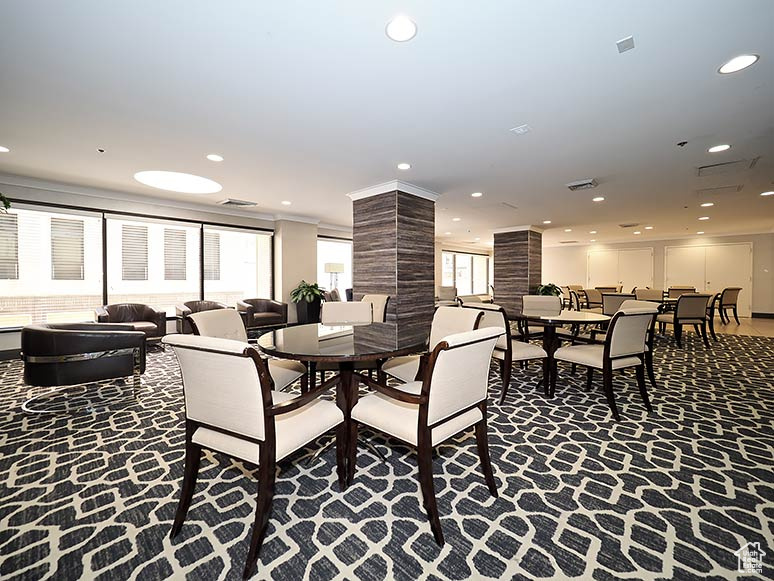 Carpeted dining space with decorative columns and recessed lighting