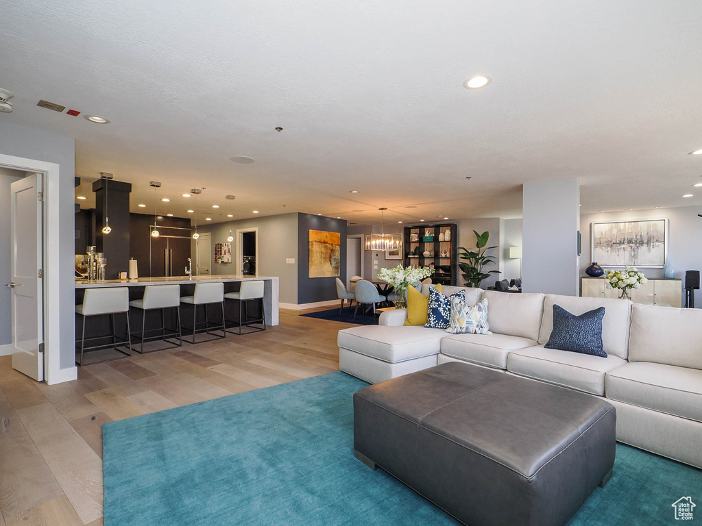 Living room featuring light wood-style floors, recessed lighting, baseboards, and a chandelier