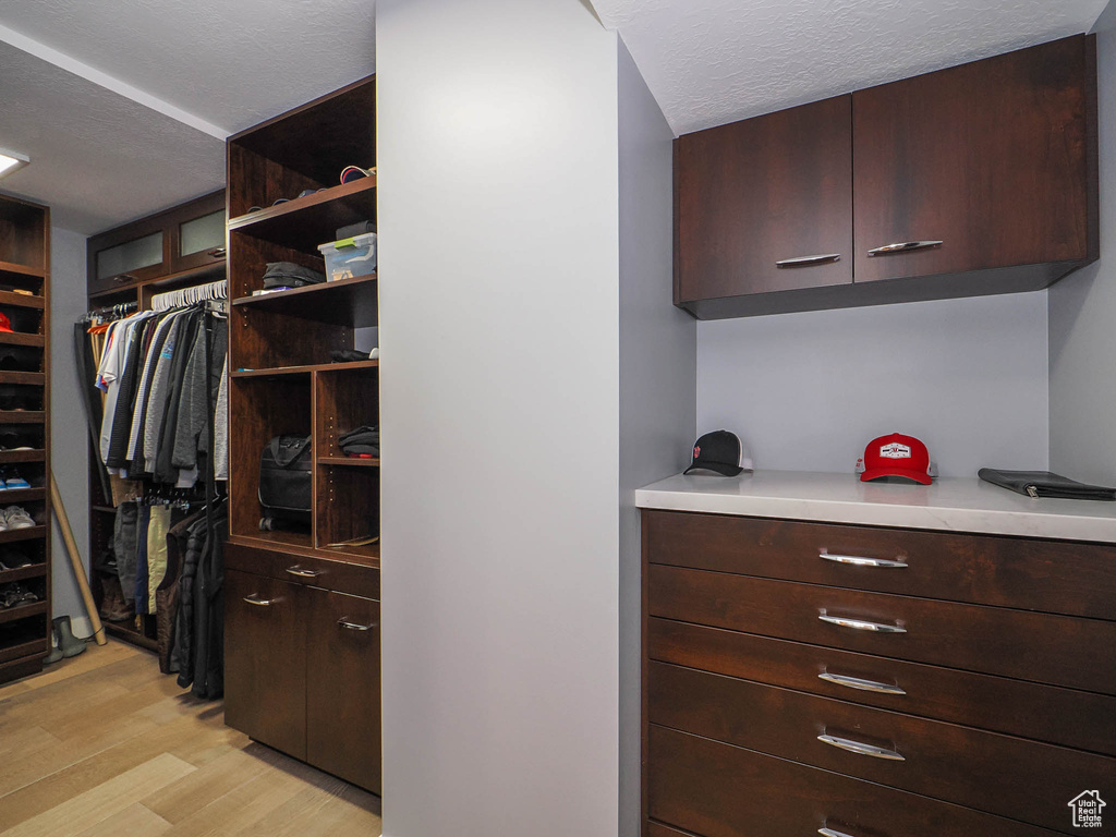 Walk in closet with light wood-style flooring