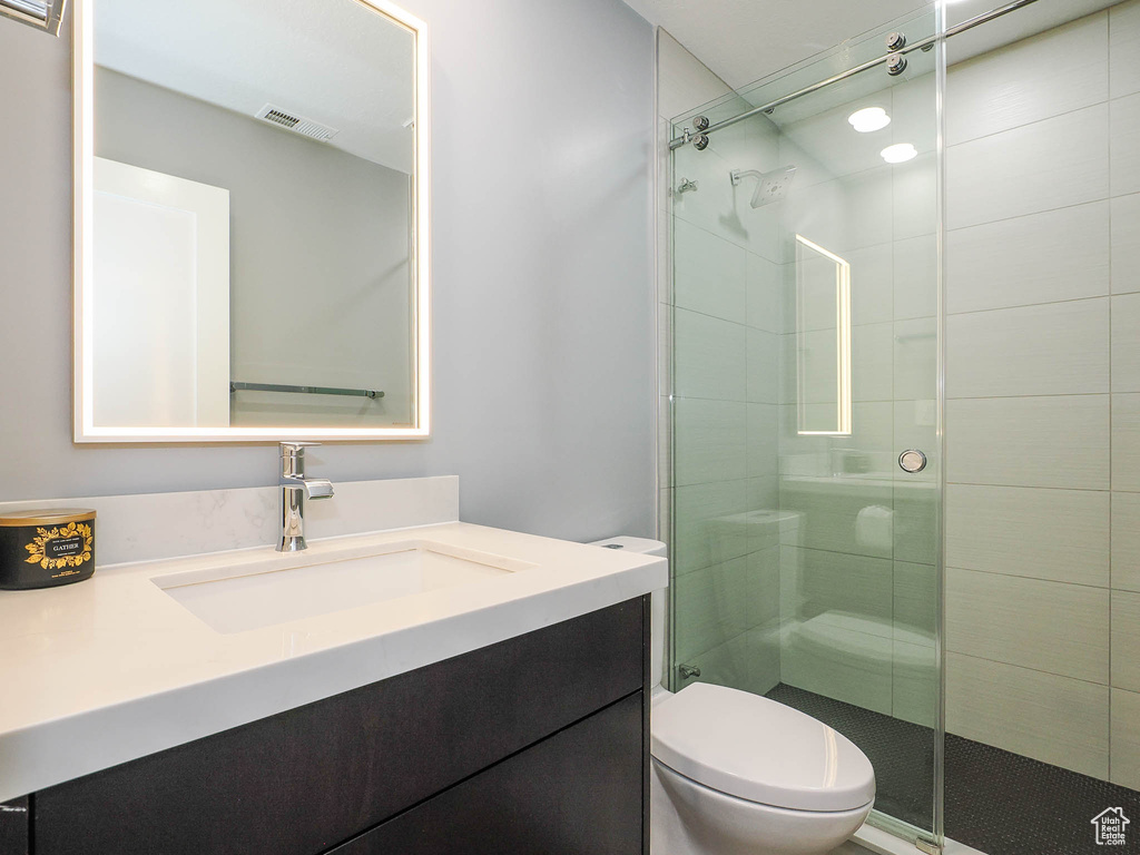 Bathroom featuring toilet, vanity, and a stall shower