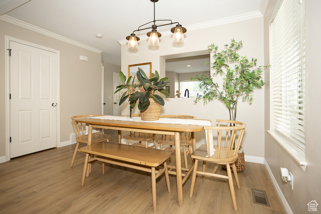 Dining area with wood finished floors, ornamental molding, baseboards, and a chandelier
